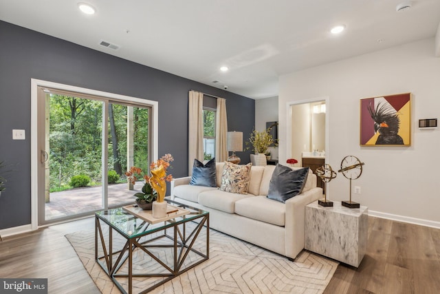 living room with baseboards, visible vents, and wood finished floors