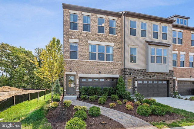 multi unit property featuring concrete driveway, brick siding, an attached garage, and fence