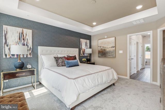 carpeted bedroom featuring baseboards, recessed lighting, a raised ceiling, and visible vents