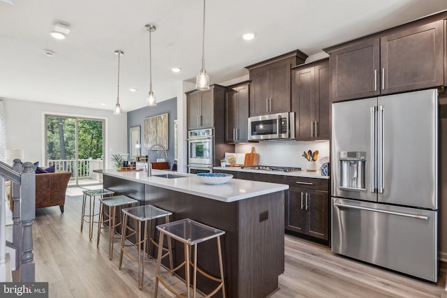 kitchen featuring a kitchen breakfast bar, dark brown cabinetry, appliances with stainless steel finishes, and a sink