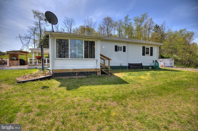 back of property with entry steps and a yard