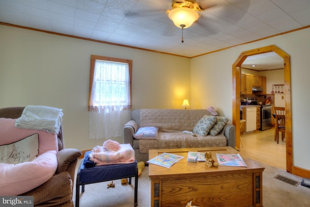 living room featuring visible vents, ornamental molding, arched walkways, and light carpet
