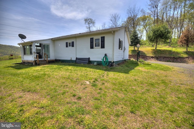 rear view of property with a sunroom, a yard, and entry steps