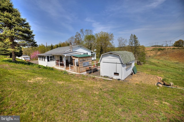 back of house featuring a storage shed, a yard, and an outdoor structure