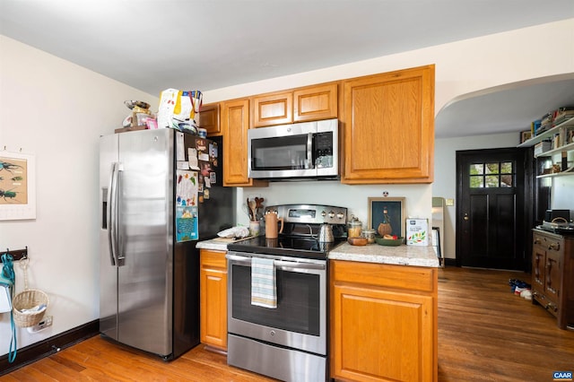 1210 Meriwether St, Charlottesville, VA 22902 - kitchen featuring arched walkways, appliances with stainless steel finishes, wood finished floors, and brown cabinets