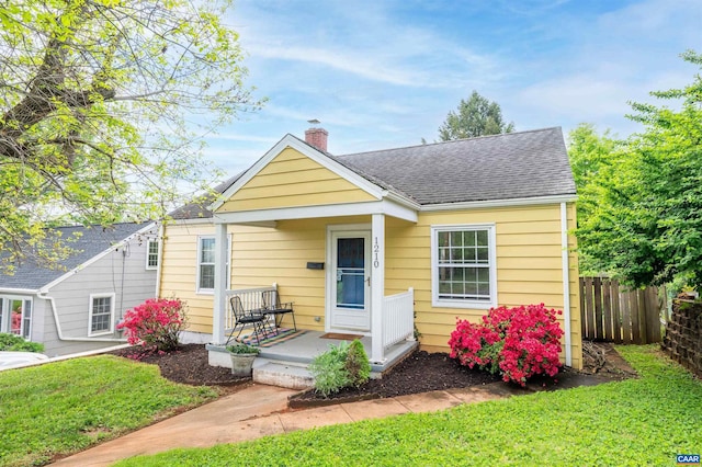 1210 Meriwether St, Charlottesville, VA 22902 - bungalow-style home featuring covered porch, a chimney, a front yard, roof with shingles, and fence