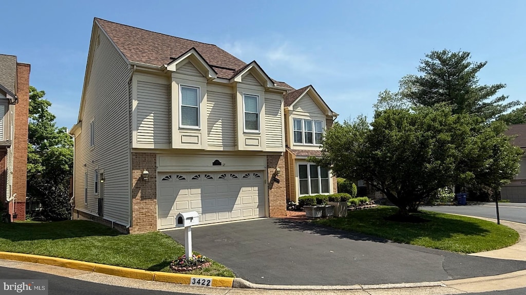 view of front of property featuring an attached garage, a front yard, driveway, and brick siding