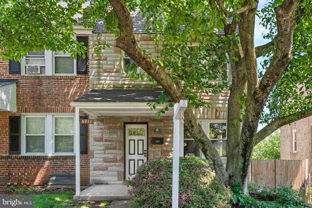 view of front facade with fence, stone siding, and brick siding
