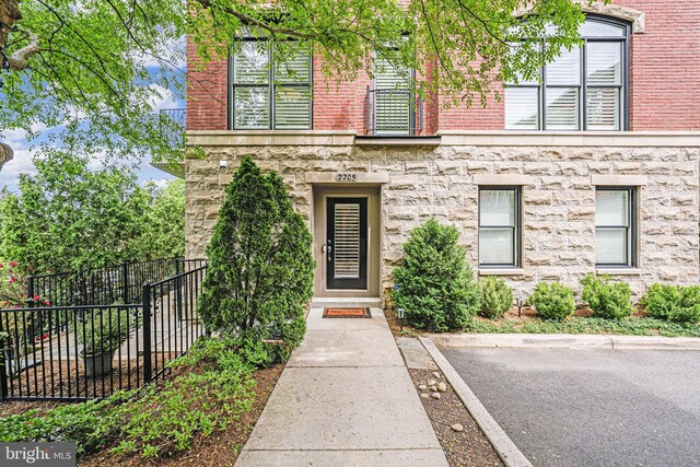 doorway to property featuring fence and stone siding