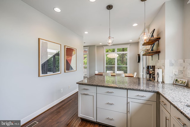 kitchen featuring a peninsula, dark wood-type flooring, baseboards, hanging light fixtures, and light stone countertops