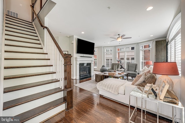 living room featuring ceiling fan, hardwood / wood-style floors, stairway, recessed lighting, and a glass covered fireplace