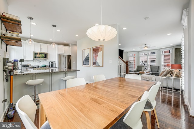 dining space featuring dark wood-style flooring, ceiling fan, recessed lighting, stairs, and baseboards