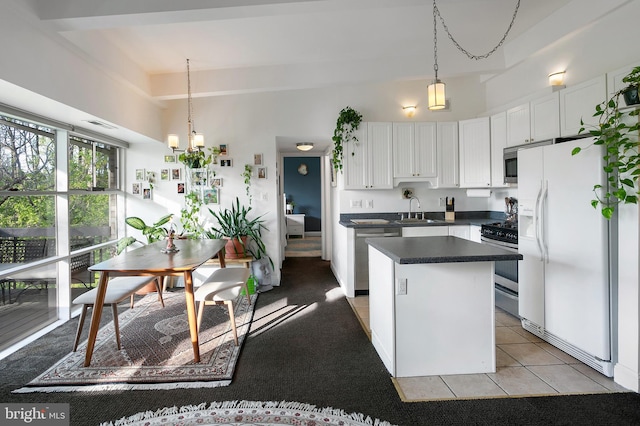 kitchen featuring dark countertops, appliances with stainless steel finishes, a sink, a center island, and white cabinetry