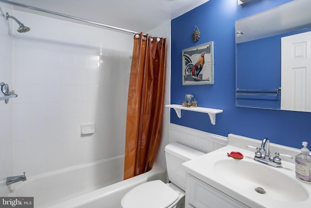 full bathroom with vanity, toilet, wainscoting, and shower / tub combo with curtain