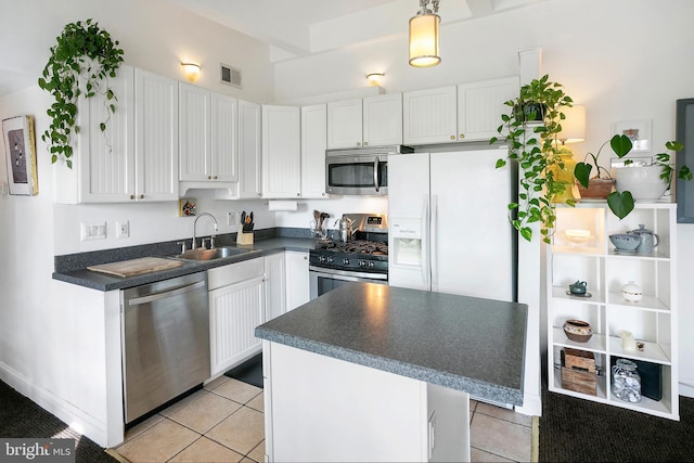 kitchen featuring dark countertops, a sink, stainless steel appliances, white cabinetry, and visible vents