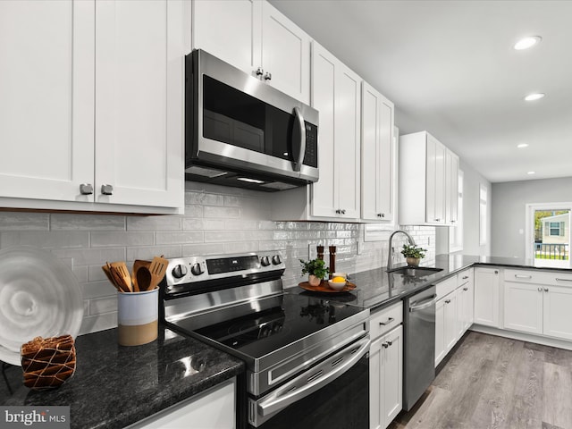 36986 Blue Teal Rd, Selbyville, DE 19975 - kitchen featuring a sink, white cabinets, dark stone counters, stainless steel appliances, and light wood-style flooring