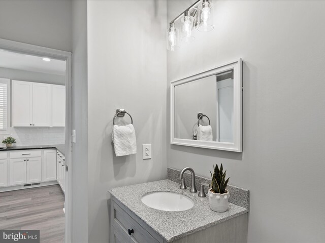 36986 Blue Teal Rd, Selbyville, DE 19975 - bathroom with vanity, wood finished floors, visible vents, and tasteful backsplash