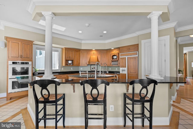 285 Eagle Hill Rd, Pasadena, MD 21122 - kitchen with white double oven, paneled refrigerator, light tile patterned floors, ornate columns, and a spacious island