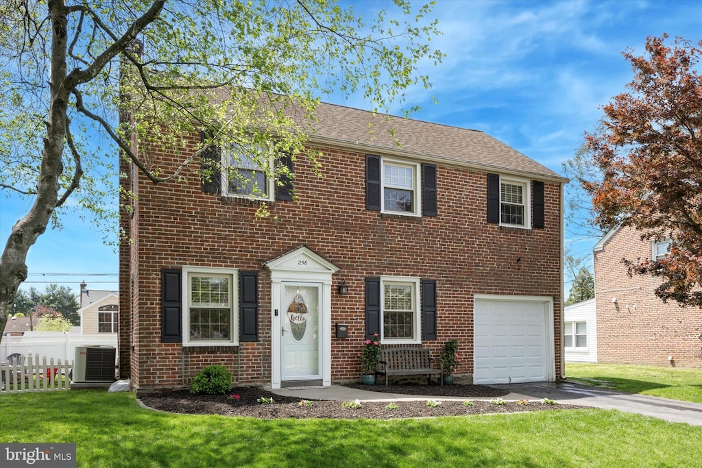 colonial house with central air condition unit, fence, driveway, and a front lawn