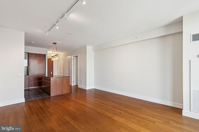 kitchen with track lighting, dark countertops, baseboards, a chandelier, and dark wood finished floors