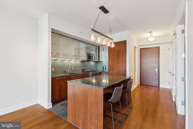 kitchen featuring a breakfast bar area, dark countertops, appliances with stainless steel finishes, modern cabinets, and a center island
