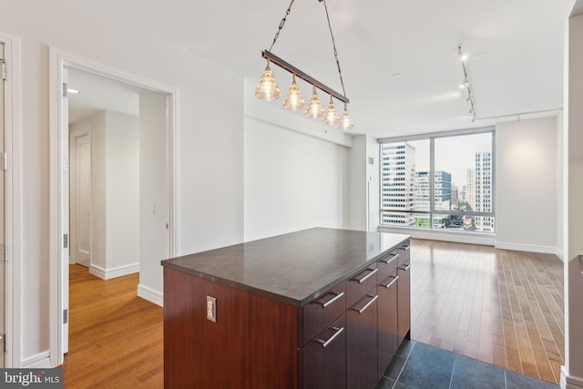 kitchen with dark countertops, baseboards, wood finished floors, and open floor plan