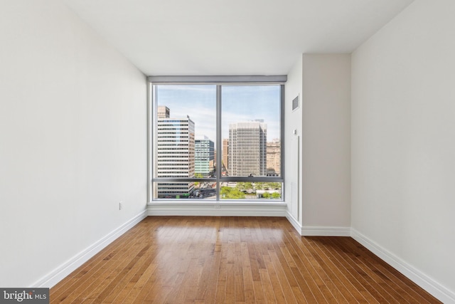 spare room featuring baseboards, wood-type flooring, a view of city, and visible vents