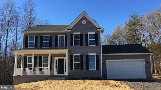 colonial house featuring an attached garage, a porch, and driveway