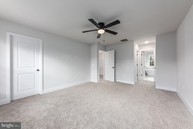 unfurnished bedroom with baseboards, light carpet, connected bathroom, and visible vents
