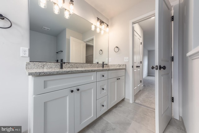 bathroom with double vanity, baseboards, a sink, and visible vents