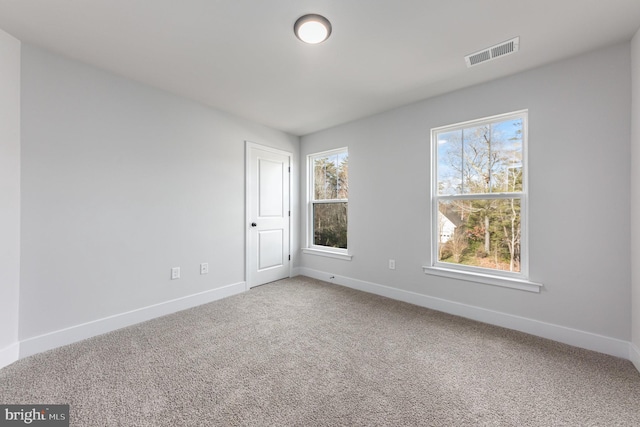 carpeted spare room featuring baseboards and visible vents