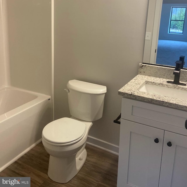 full bath with vanity, wood finished floors, toilet, baseboards, and a bathing tub