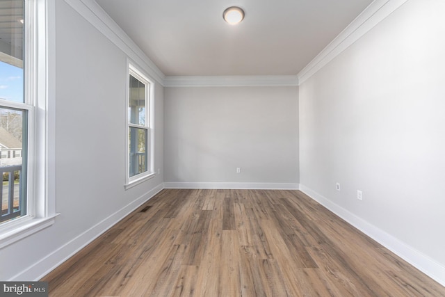 empty room featuring baseboards, ornamental molding, wood finished floors, and visible vents