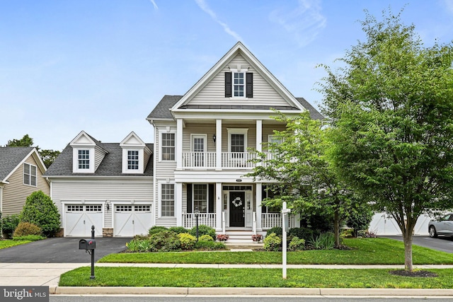 greek revival inspired property featuring covered porch, driveway, a front yard, a balcony, and a shingled roof