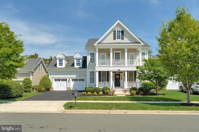 greek revival house with a porch, aphalt driveway, an attached garage, and a front yard