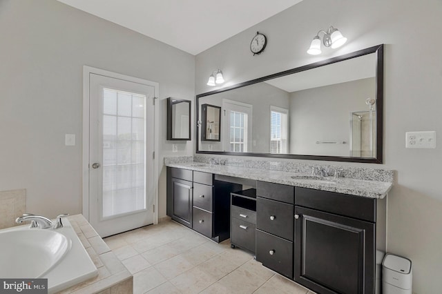 bathroom featuring a sink, a bath, tile patterned flooring, and double vanity
