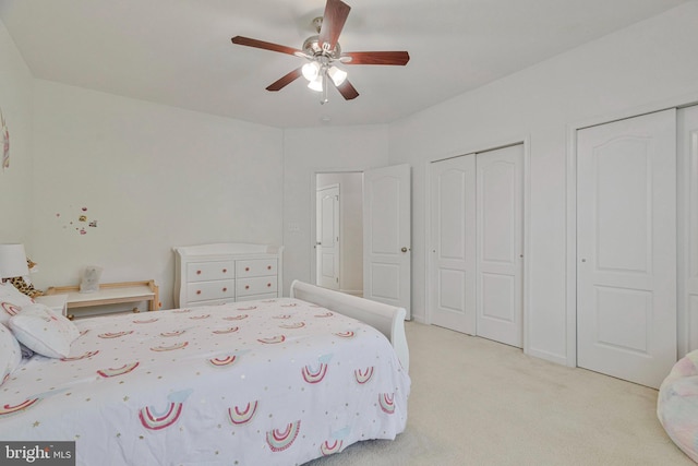 bedroom featuring multiple closets, a ceiling fan, and light colored carpet