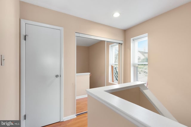 corridor featuring light wood-style flooring, recessed lighting, an upstairs landing, and baseboards