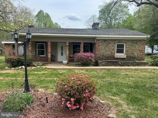single story home featuring a chimney, a porch, brick siding, and a front yard