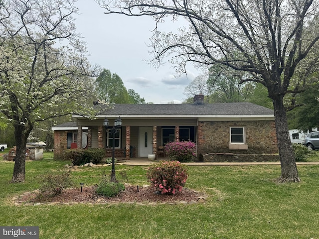 ranch-style home featuring covered porch, a chimney, brick siding, and a front yard