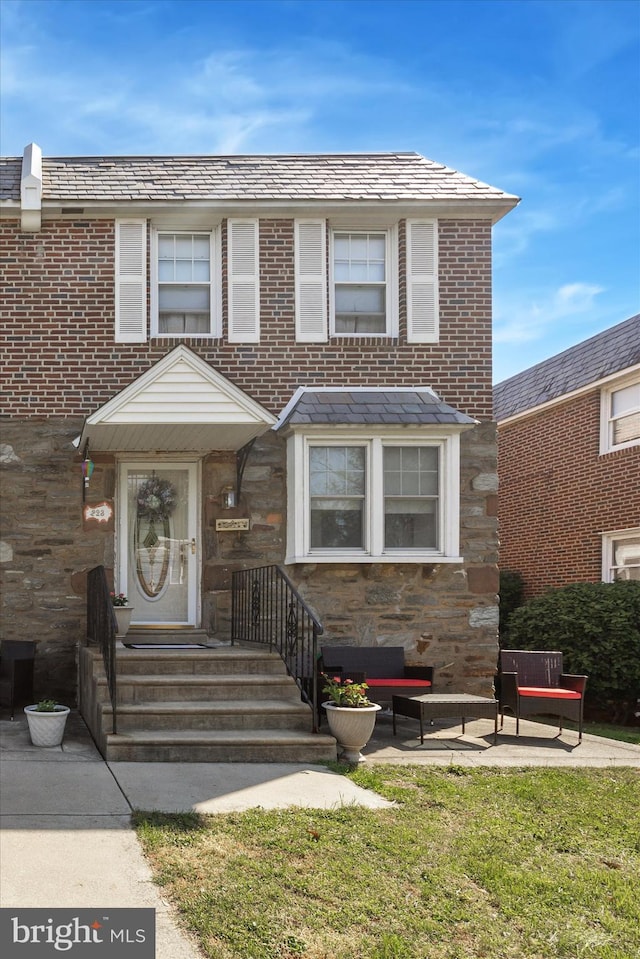 multi unit property with a front lawn and stone siding