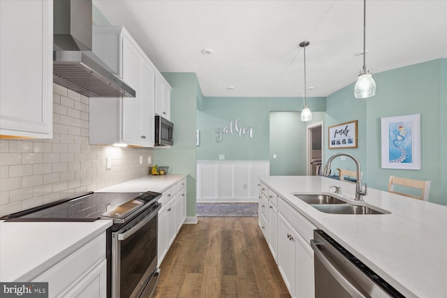 kitchen featuring a sink, wall chimney exhaust hood, white cabinetry, dark wood-style floors, and appliances with stainless steel finishes