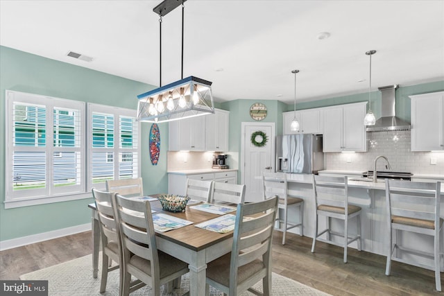 dining area featuring light wood-style floors, visible vents, and baseboards