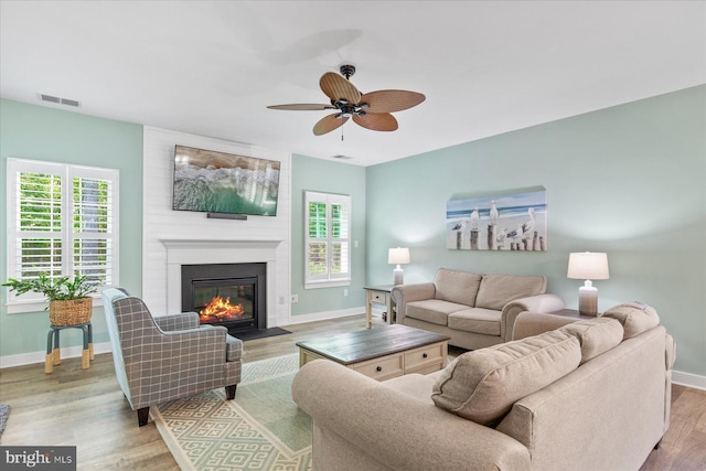 living room with a large fireplace, plenty of natural light, visible vents, and a ceiling fan