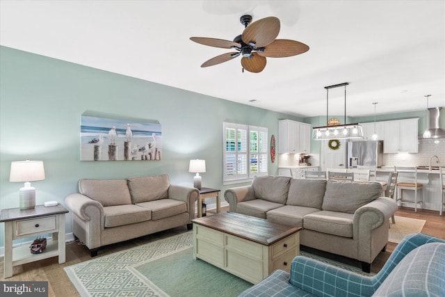 living room with ceiling fan, light wood-style flooring, and baseboards