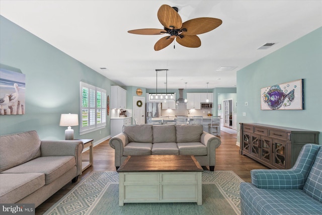 living room featuring a ceiling fan, visible vents, and wood finished floors