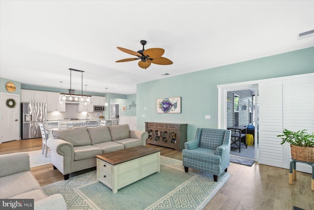 living area featuring ceiling fan, light wood-type flooring, and visible vents