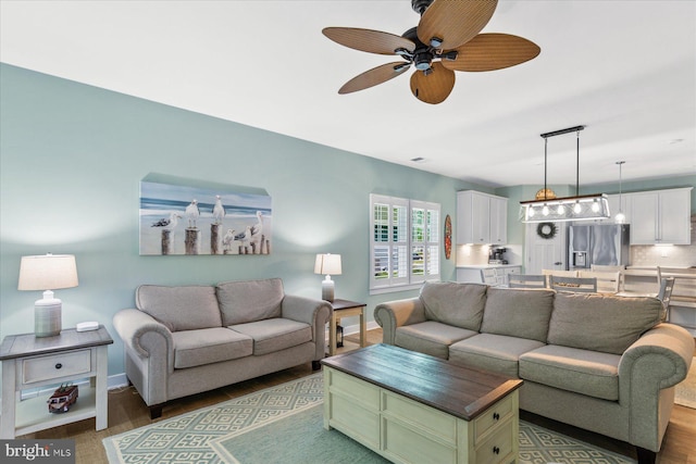 living area with wood finished floors, baseboards, and ceiling fan