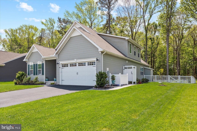 view of side of home featuring aphalt driveway, fence, an attached garage, roof with shingles, and a yard