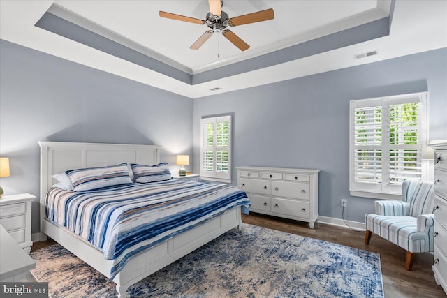 bedroom featuring wood finished floors, visible vents, ceiling fan, a raised ceiling, and baseboards